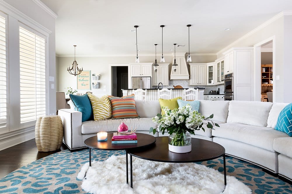 Before and After: A Fresh + Cozy Waco Living Room designed by Lesley Myrick with a custom curved sectional and colorful pillows in teal, chartreuse, and red. 