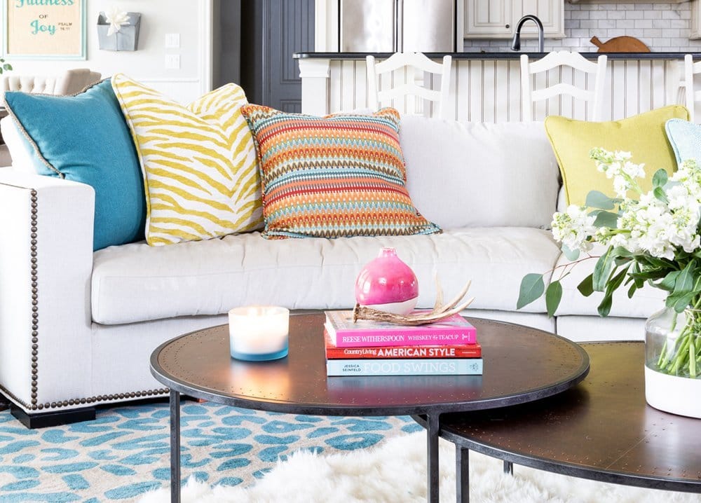 Before and After: A Fresh + Cozy Waco Living Room designed by Lesley Myrick with a custom curved sectional and colorful pillows in teal, chartreuse, and red. 