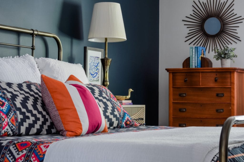 Hot pink and orange bedding in a navy master bedroom by interior designer Lesley Myrick