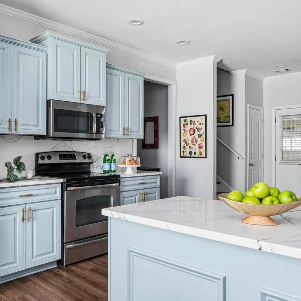 A modern kitchen featuring blue cabinets and elegant white countertops, creating a fresh and inviting atmosphere.