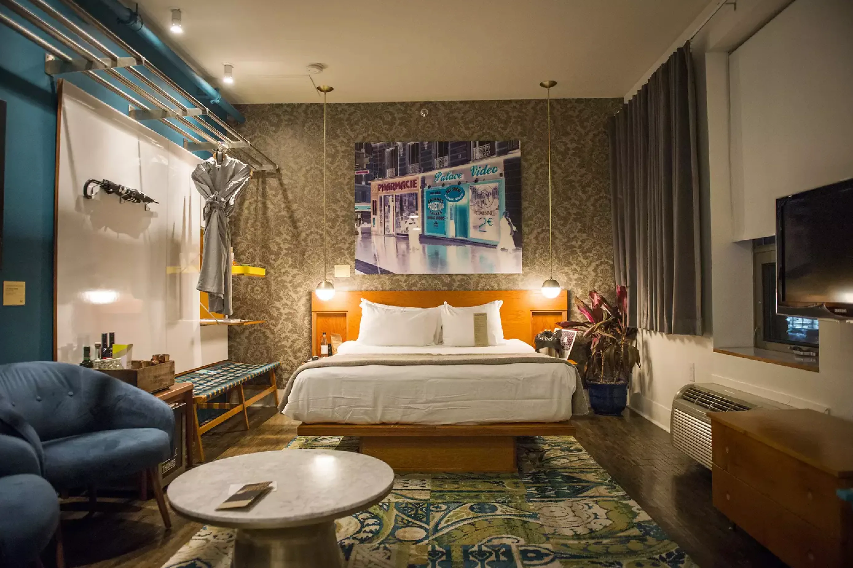 A stylish hotel room featuring a bed, a chair, and an elegant painting on the wall, inspired by the Drake Hotel, Toronto.