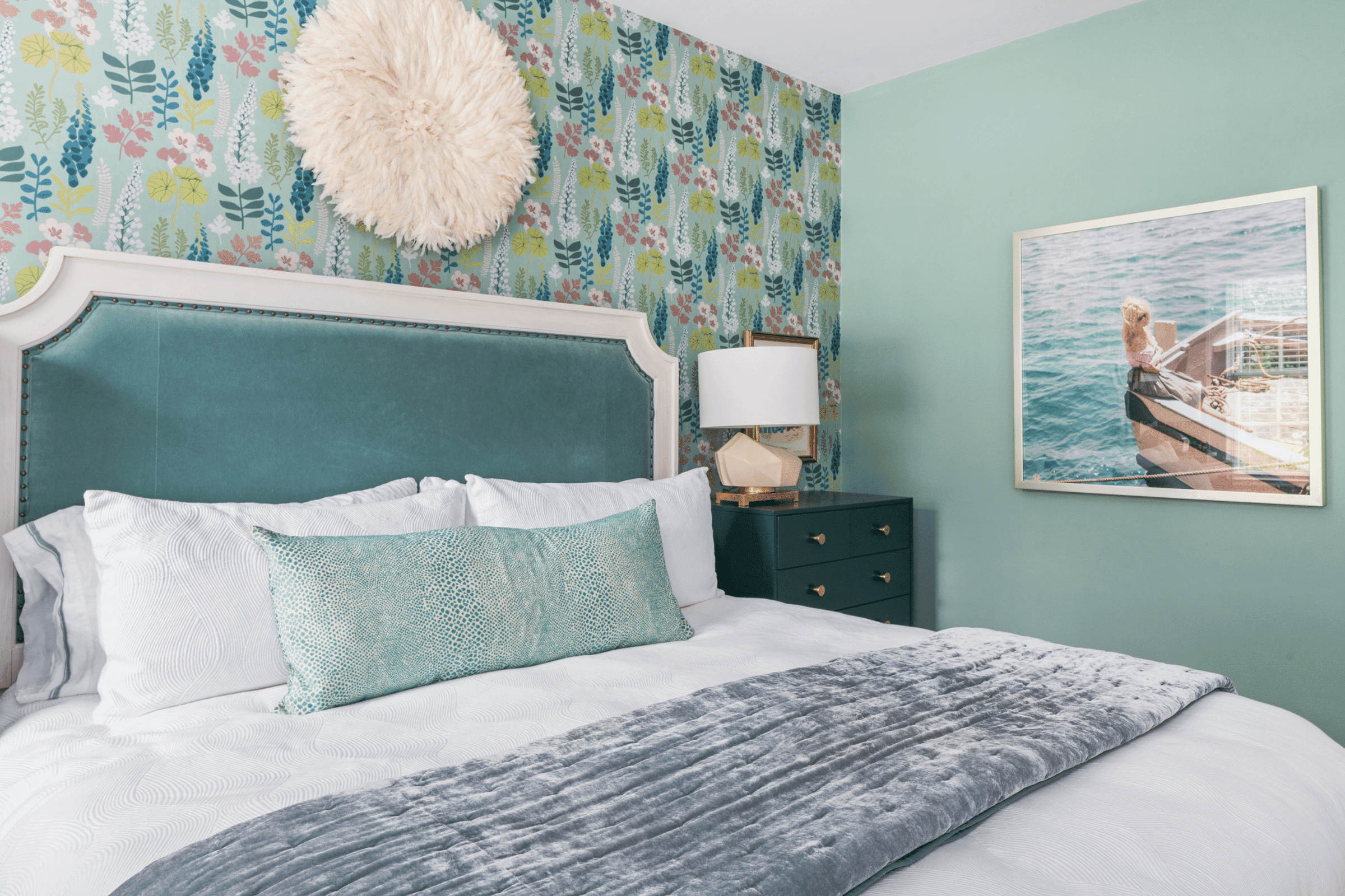 A cozy guest bedroom featuring a bed with a white headboard and floral decor in a historic Macon home.