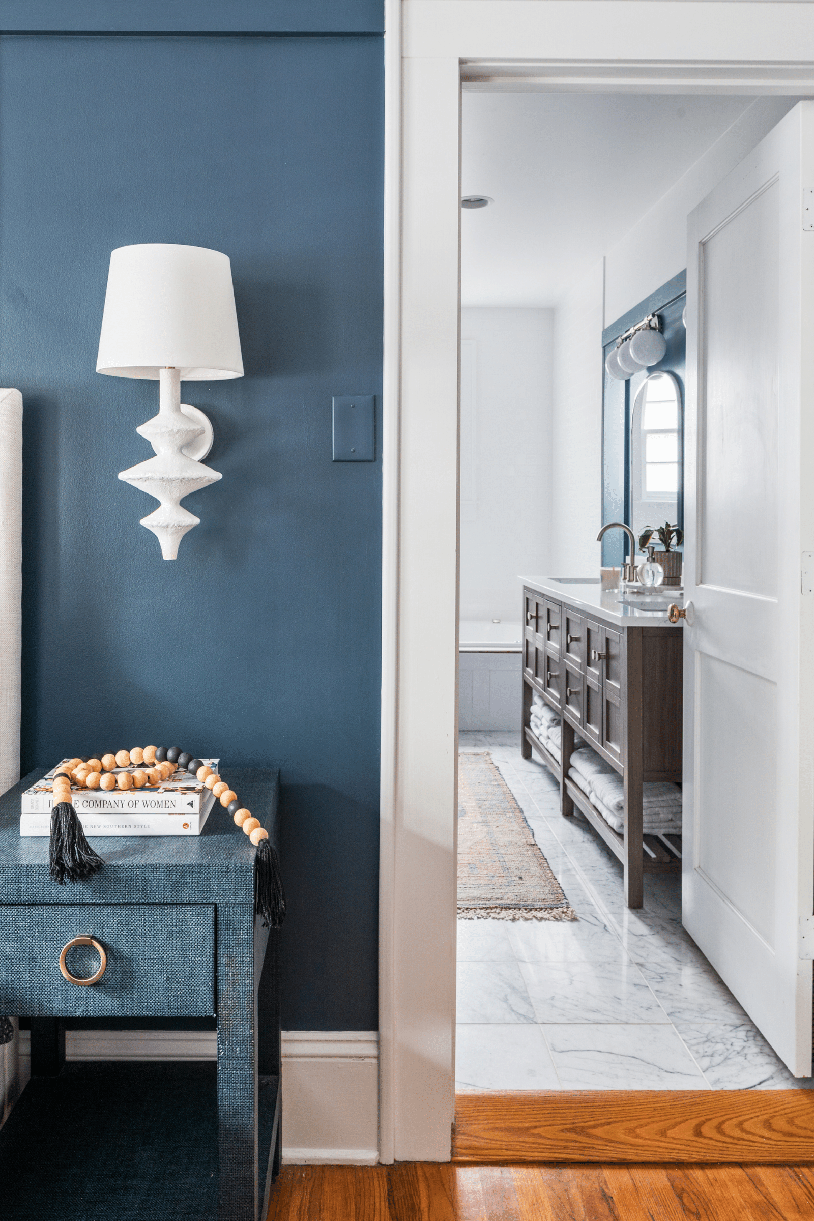 A luxe coastal-inspired blue primary bedroom with a navy grasscloth nightstand in Macon, GA, designed by Lesley Myrick Interior Design
