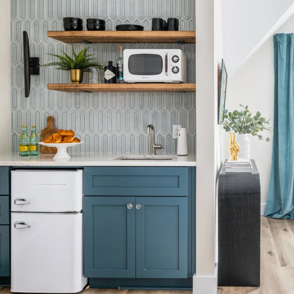A modern kitchen featuring blue cabinets and a microwave, showcasing a stylish and functional cooking space.