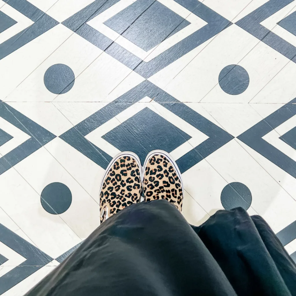 A person stands on a patterned floor, showcasing intricate designs beneath their feet.