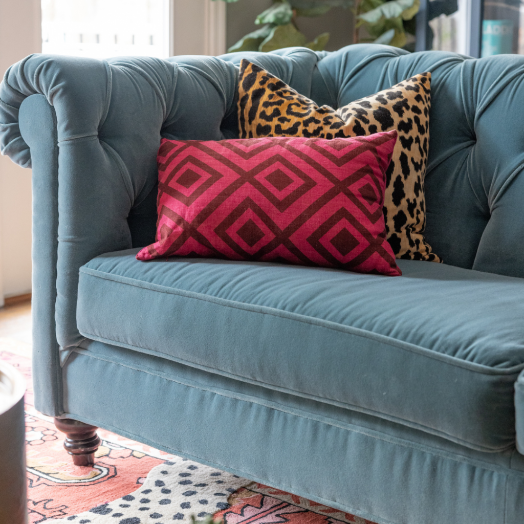 Teal sofa with leopard and pink pillows 