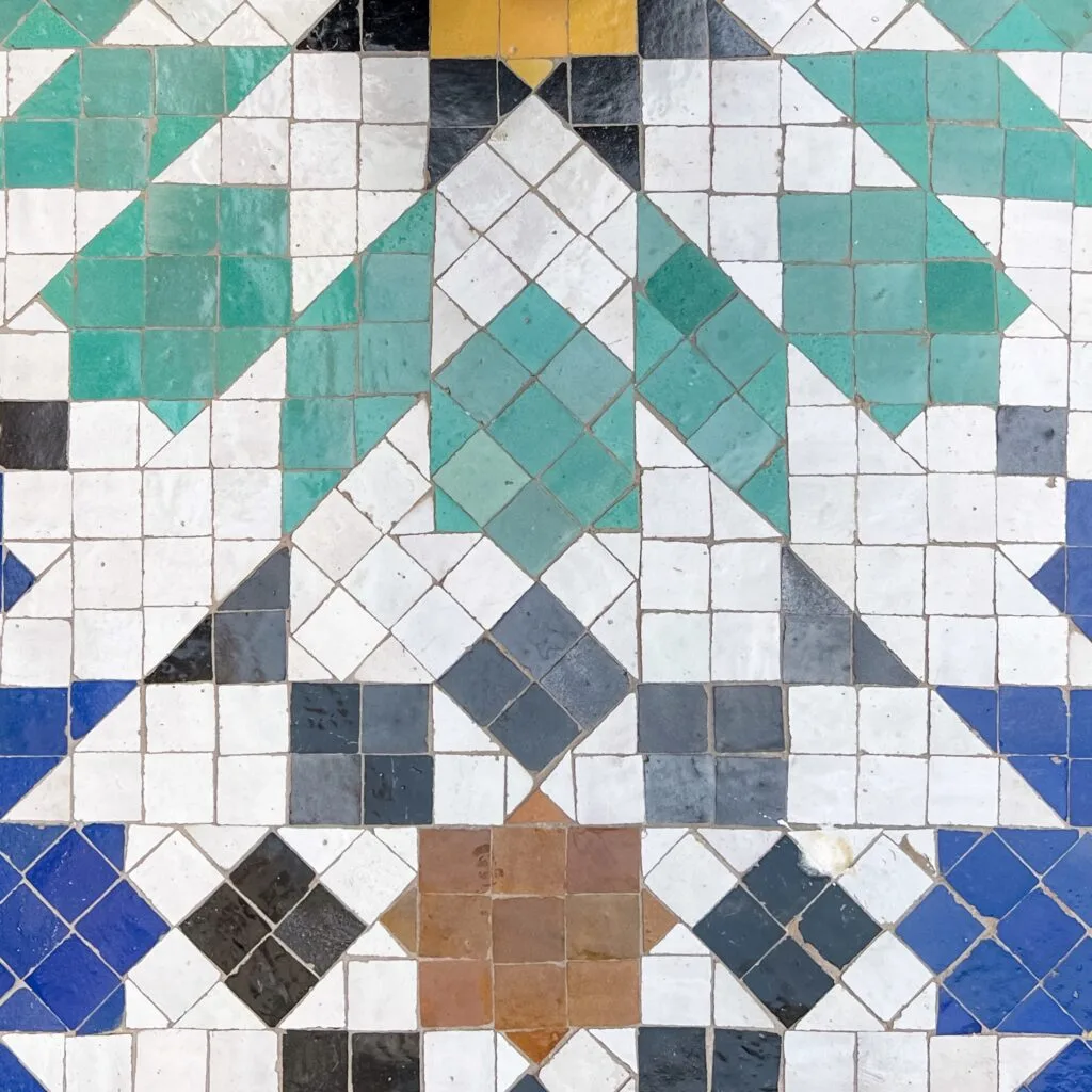 Colorful tile floor featuring intricate geometric designs in various hues, creating a vibrant and artistic pattern.