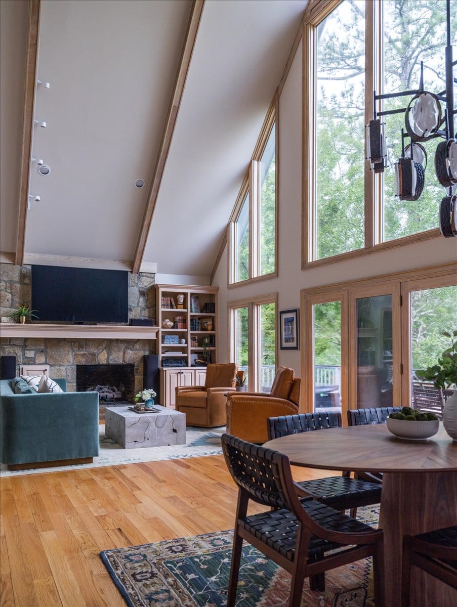 Living room and dining room with green velvet sofa, leather chairs, and bold patterned rug.