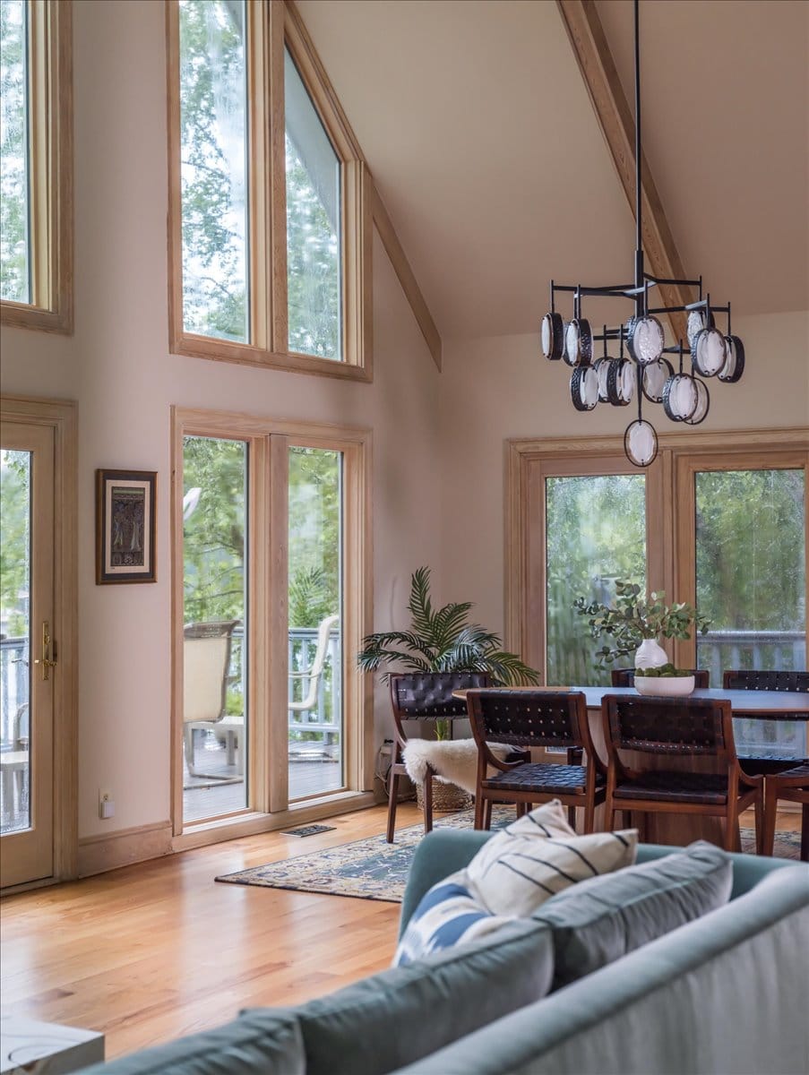 View of chandelier and dining table with full-height windows and lake view.
