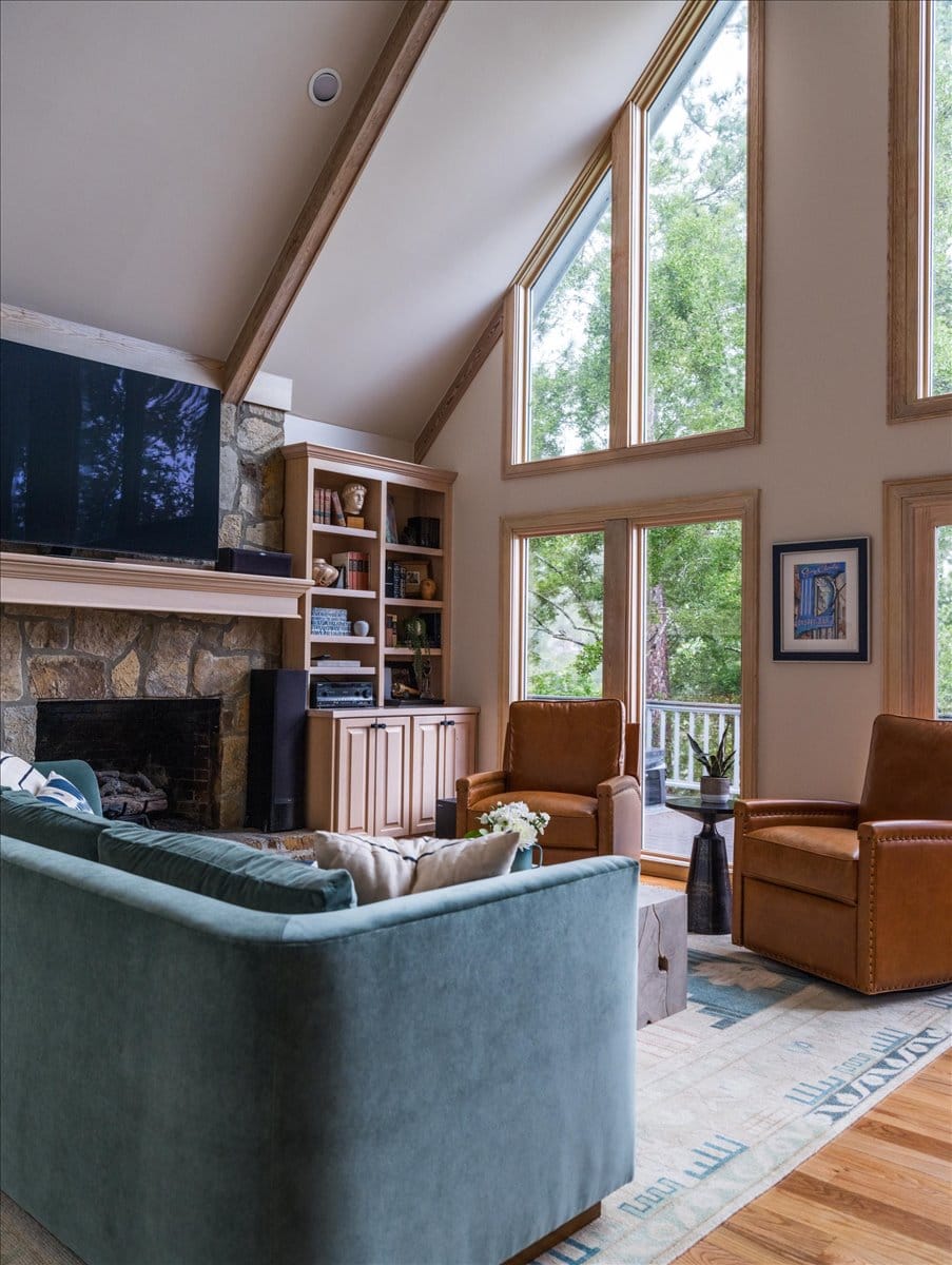 Teal sofa and camel leather chairs in Lake Sinclair living room with stone fireplace and vaulted ceiling.