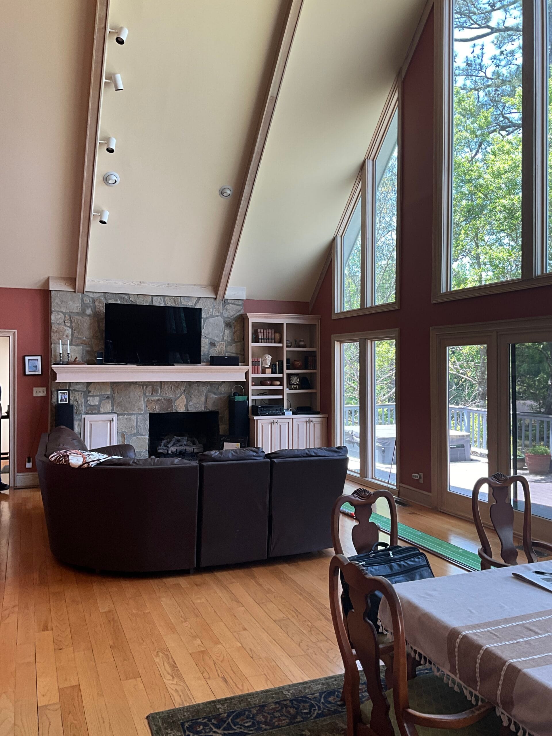Living room of Lake Sinclair home before renovation, featuring dark leather furniture and red walls.