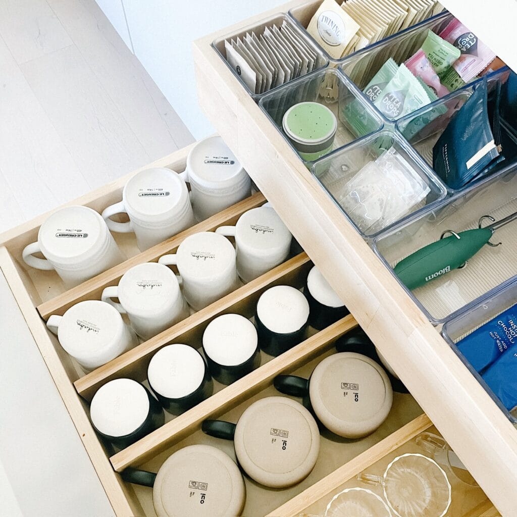 Drawer organization system with mugs, tea bags, and accessories neatly arranged in custom dividers.
