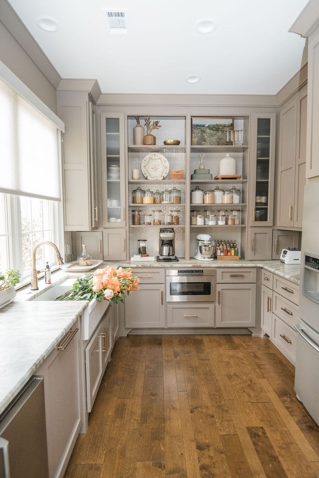 Luxury kitchen pantry with labeled glass jars, appliances, and neatly styled shelves.