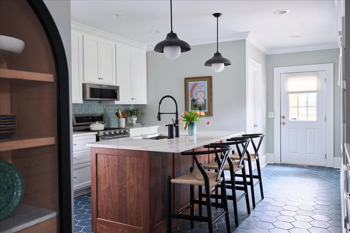 A kitchen with dark blue hex tiles, a warm walnut island, and original art by Macon GA Interior Designer Lesley Myrick.